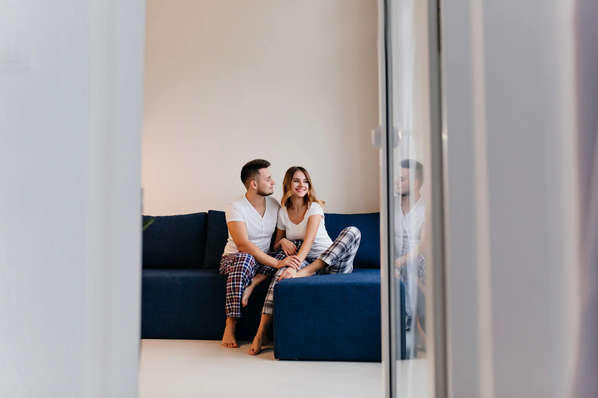 Inspired Girl In Checkered Pants Sitting On Couch With Husband. Indoor Photo Of Smiling Man And Woman Chilling In Weekend Morning..